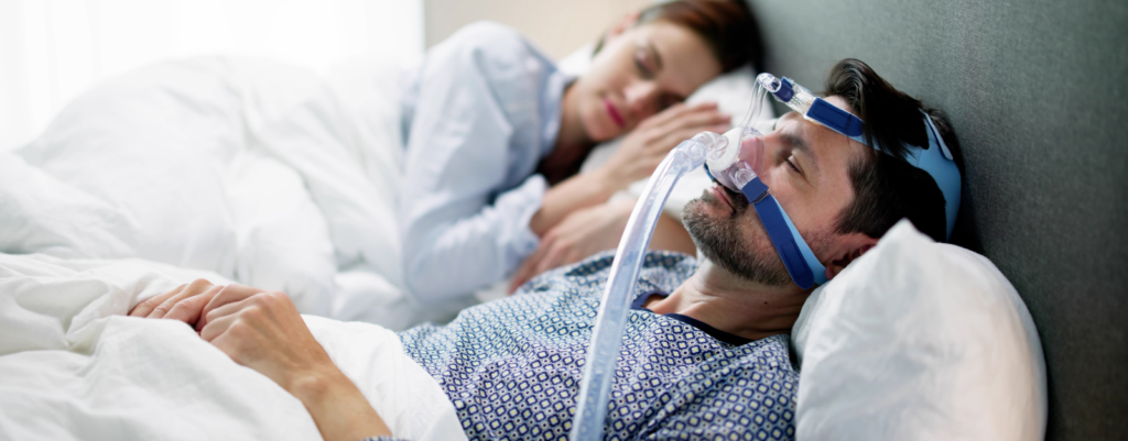 A man wearing a ventilation mask while asleep in bed.